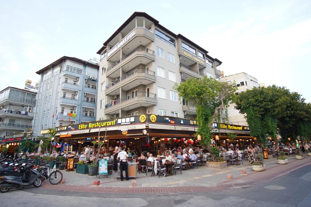 a group of people sitting at tables in front of a building at Havana Apart Hotel in Alanya