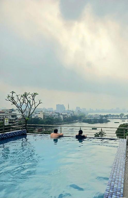 two people sitting in a swimming pool overlooking a river at Luxe Paradise Suites Hotel & Spa in Hanoi