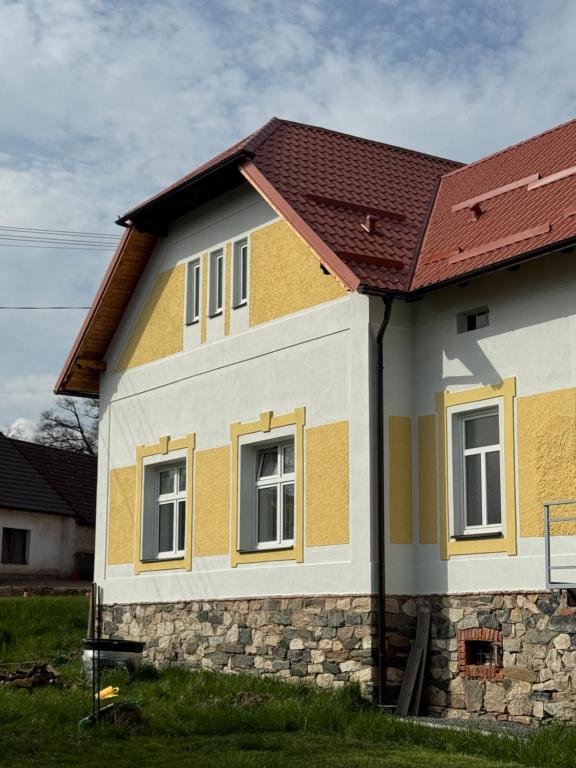 a yellow and white house with a red roof at Statek Osmička in Dolní Hořice