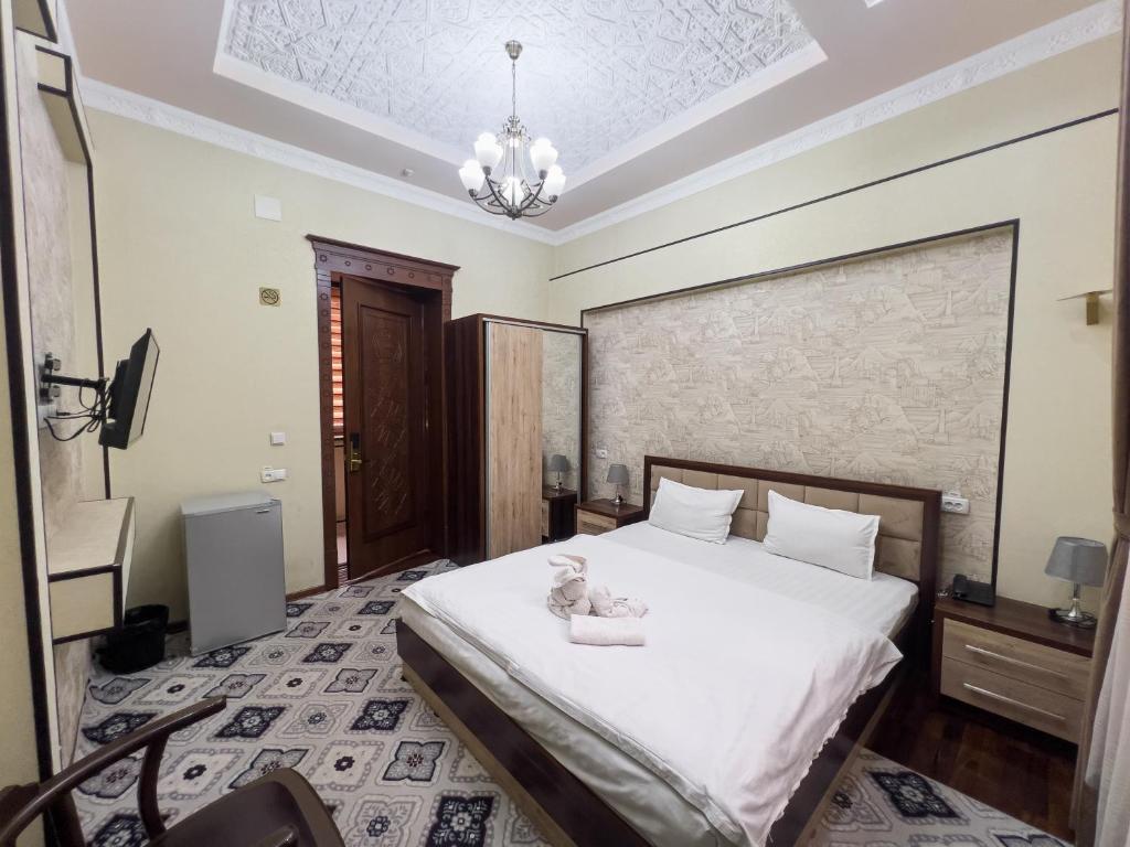 a bedroom with a large white bed with a chandelier at Hotel Gold Begim in Fergana