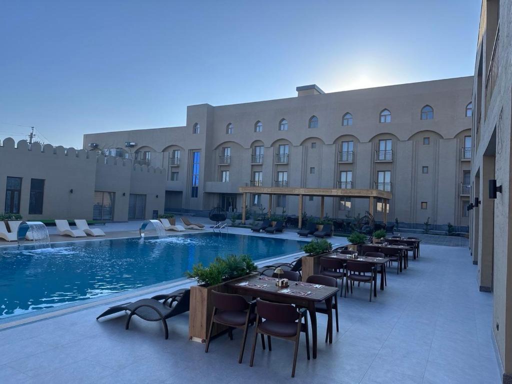a hotel with tables and chairs next to a swimming pool at Lazgi Boutique & Spa Hotel in Khiva
