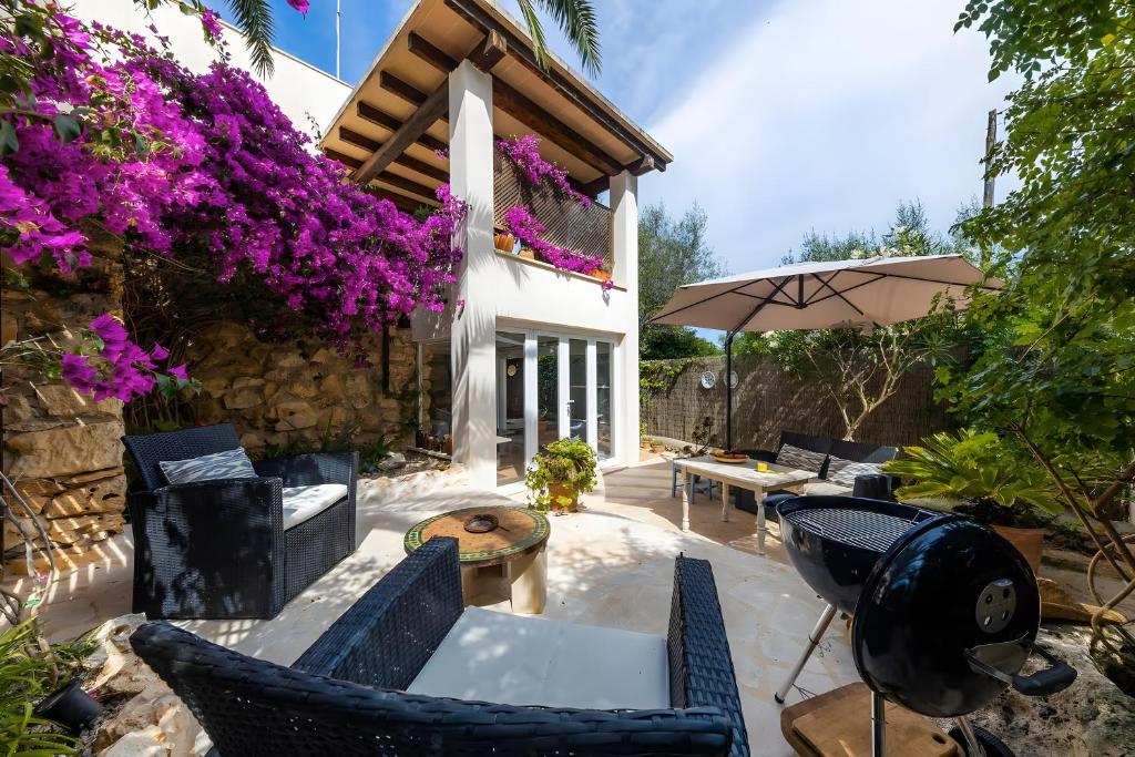 a patio with chairs and an umbrella and flowers at Cel Pins in Portopetro