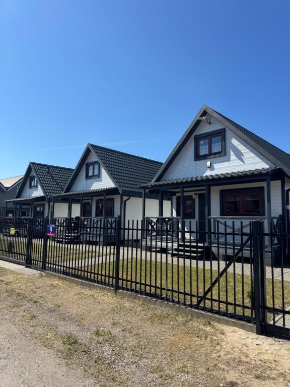 a black fence in front of a house at Domki Prima Baltic in Sarbinowo