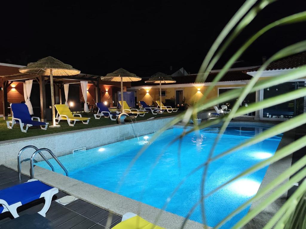 a swimming pool at night with chairs and umbrellas at Quinta Salinas - Puro Prazer in Aveiro