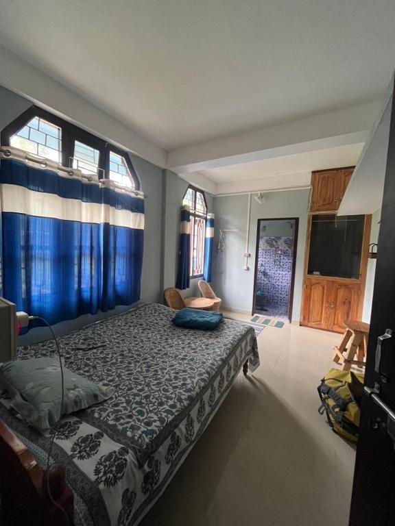 a bedroom with a large bed with blue curtains at Tani Adventure in Ziro