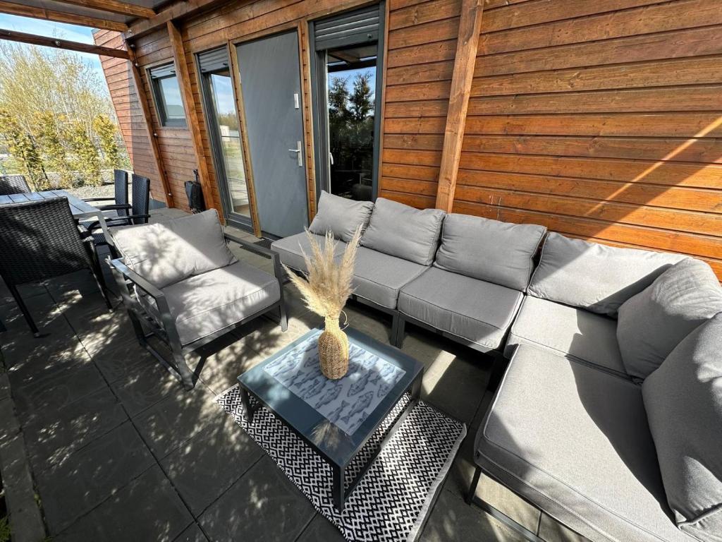 a patio with a couch and a table and chairs at Baltic Lark Gąski domek 30m2, taras zadaszony 27m2 ogródek klimatyzacja in Gąski