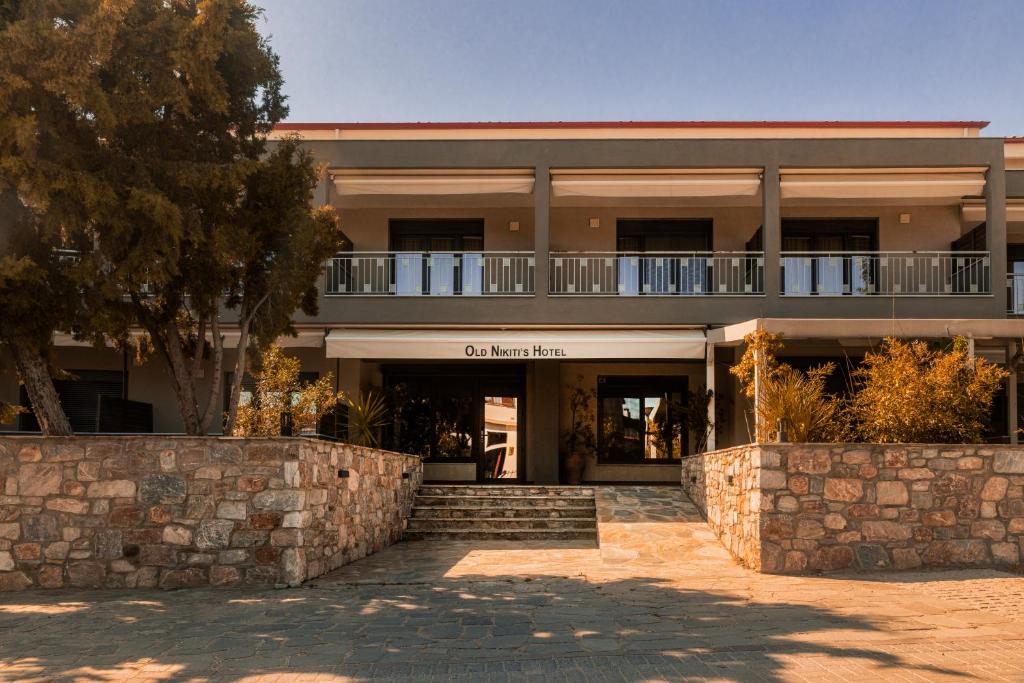 a large building with a stone wall in front of it at Old Nikiti's Hotel in Nikiti
