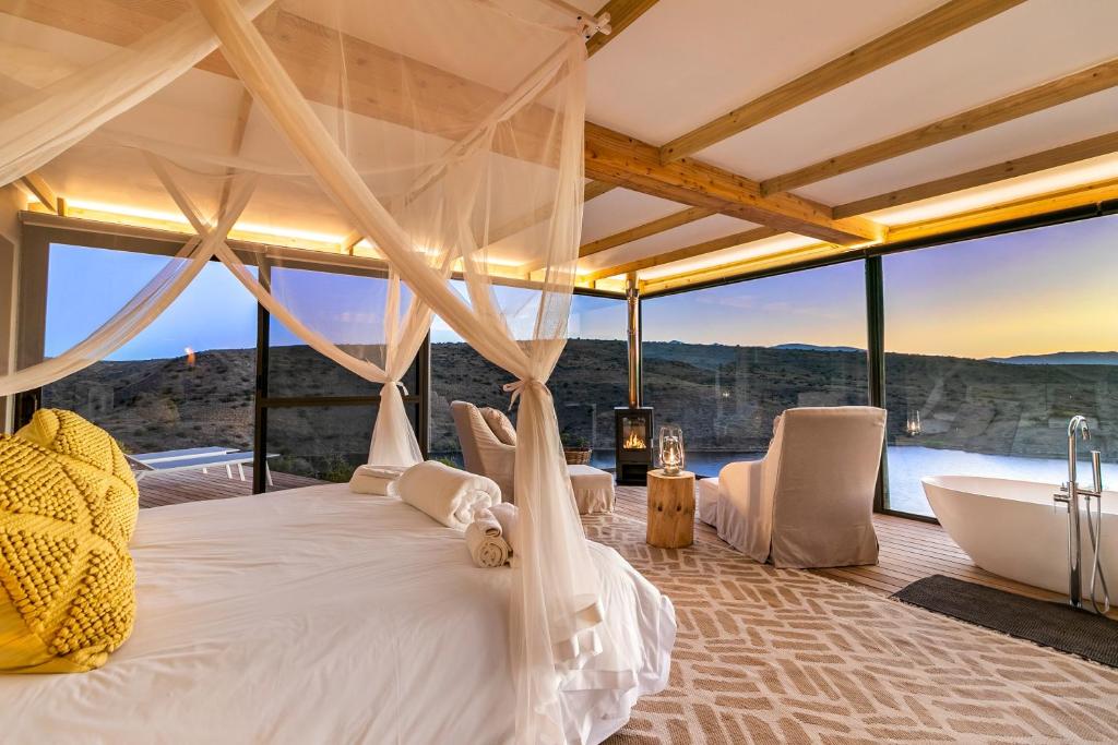 a bedroom with a tub and a bed with a view at Aardvark Bioreserve in Ladismith