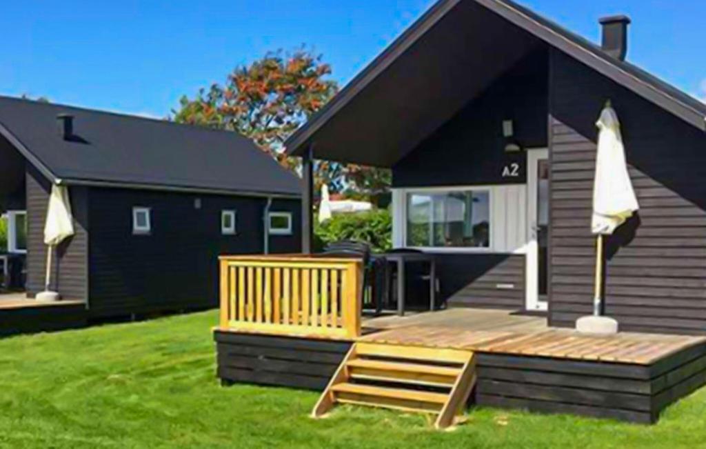 a house with a wooden deck in the yard at Nice Apartment In Farsø With Heated Swimming Pool in Farsø
