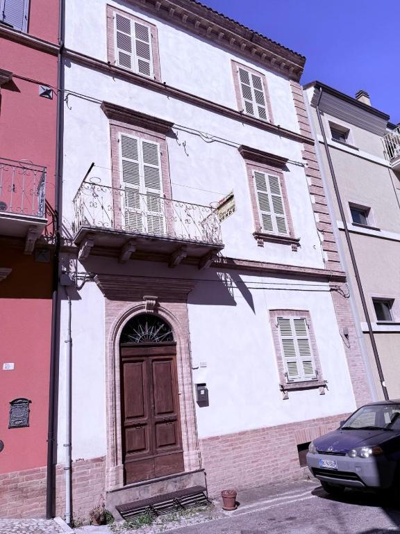 a white building with a door and a balcony at CupraScìScì in Cupra Marittima