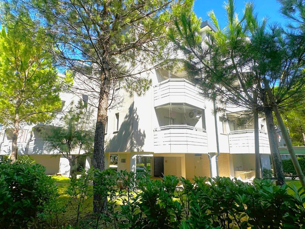 a white building with trees in front of it at NAONIS - Appartamenti in Bibione