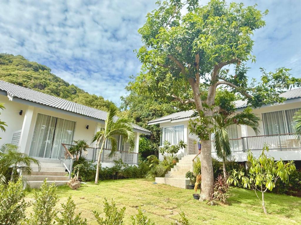 a person standing in front of a house with a tree at Baan Suan Poolsap - Haad Rin Beach in Haad Rin