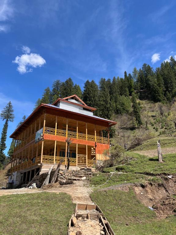 a large wooden house on a hill with trees at Peak Paradise Resort in Taobat
