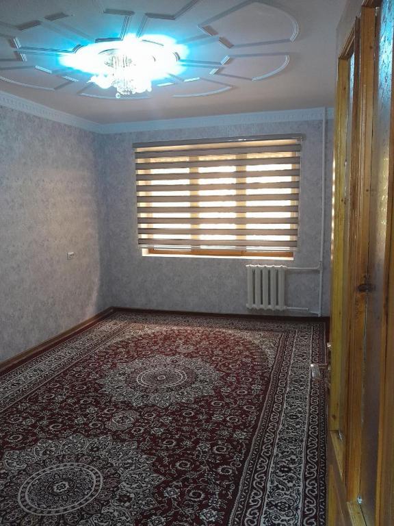 an empty room with a window and a rug at UYUT INN apartment in Samarkand