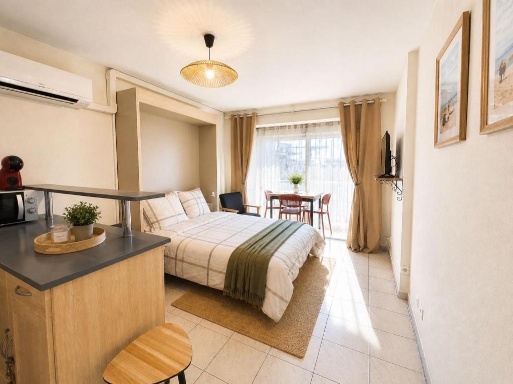 a bedroom with a bed and a table and a kitchen at Sète Studio Parking Privé Loggia in Sète