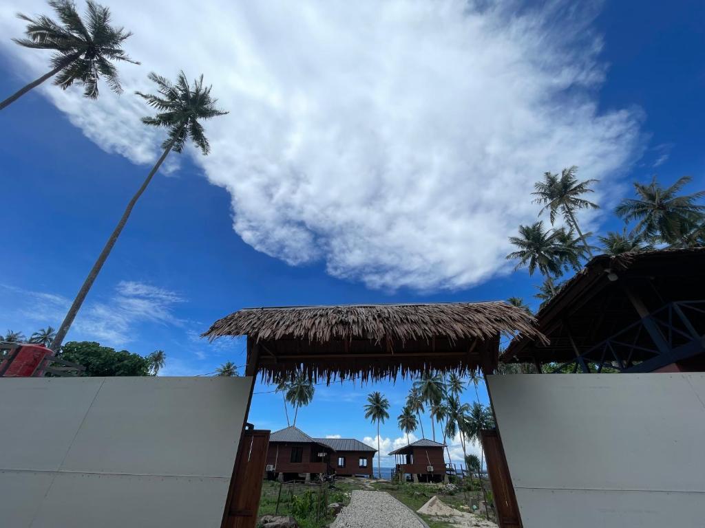 a palm tree in the sky over a white fence at Dico Surf Point- Surf Lodge in Simeulue in Lasikin