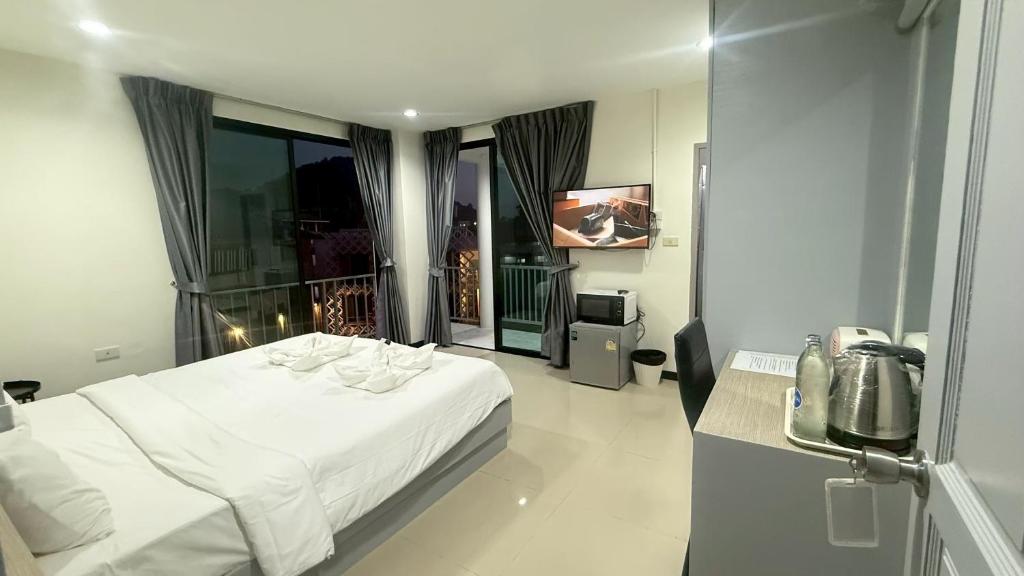 a bedroom with a white bed and a balcony at Yanud Residence in Phuket