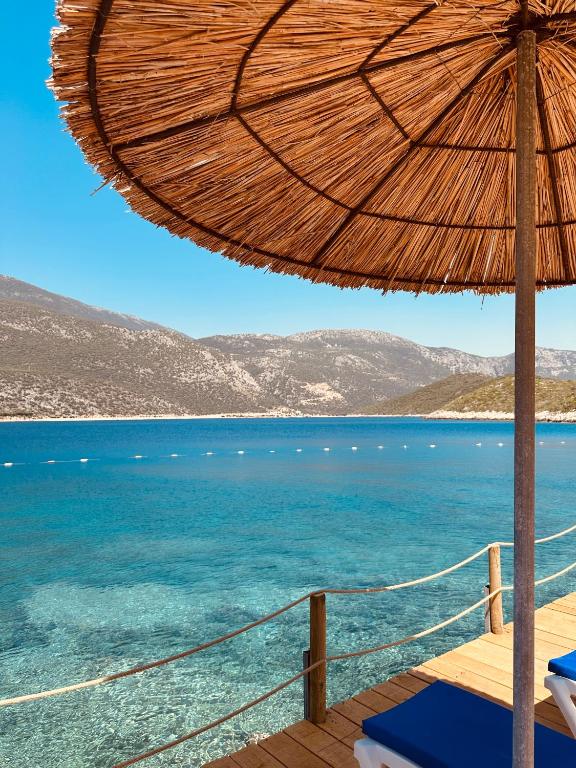 a wooden deck with an umbrella and the ocean at Club Hotel Barbarossa in Kaş