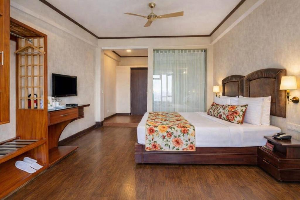a bedroom with a bed and a desk and a television at Lillium Hotel & Spa in Kalimpong