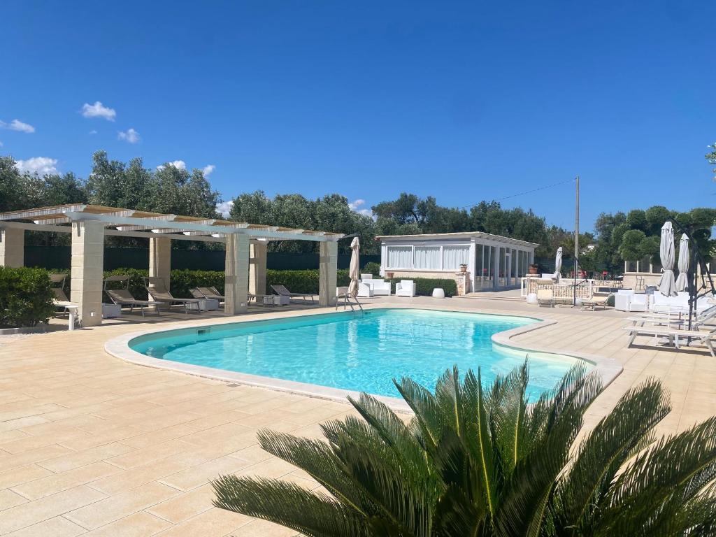 a swimming pool with chairs and umbrellas on a patio at Tenuta Verdolivo in Ostuni