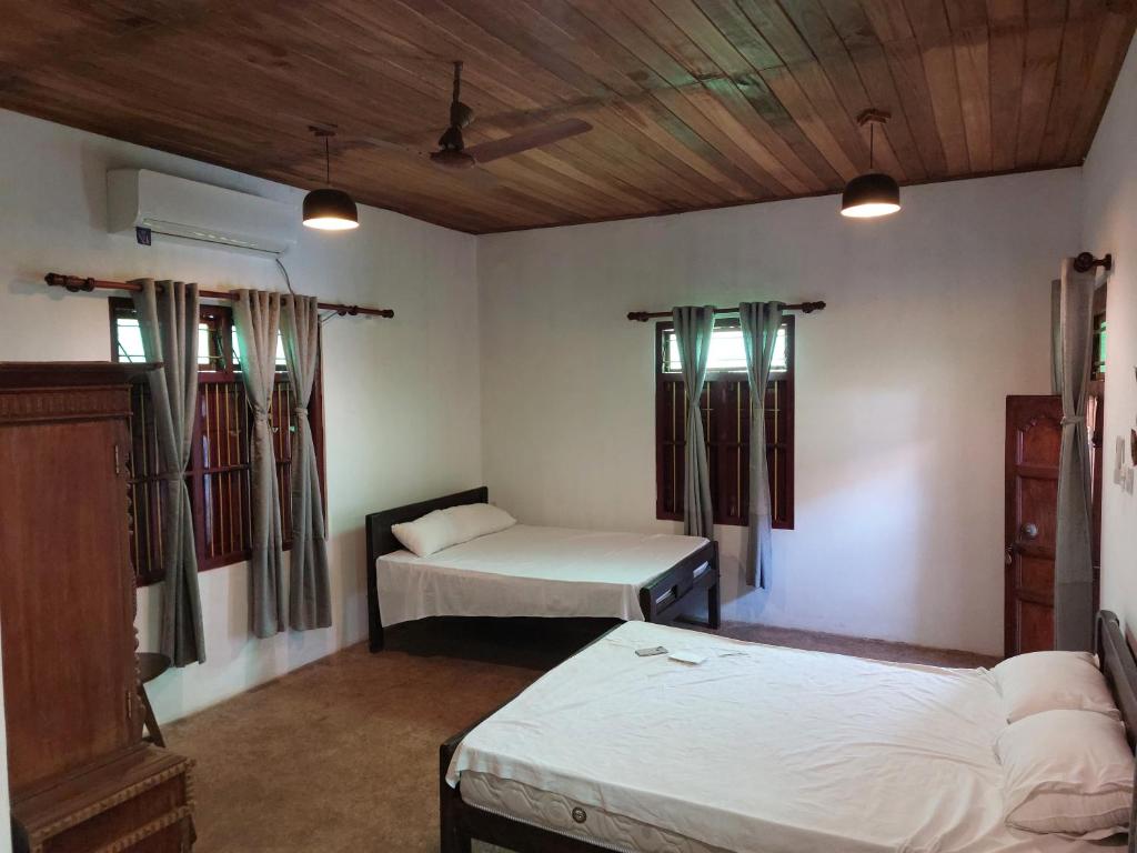 a room with two beds and two windows at Karisal Resort & Park in Jaffna