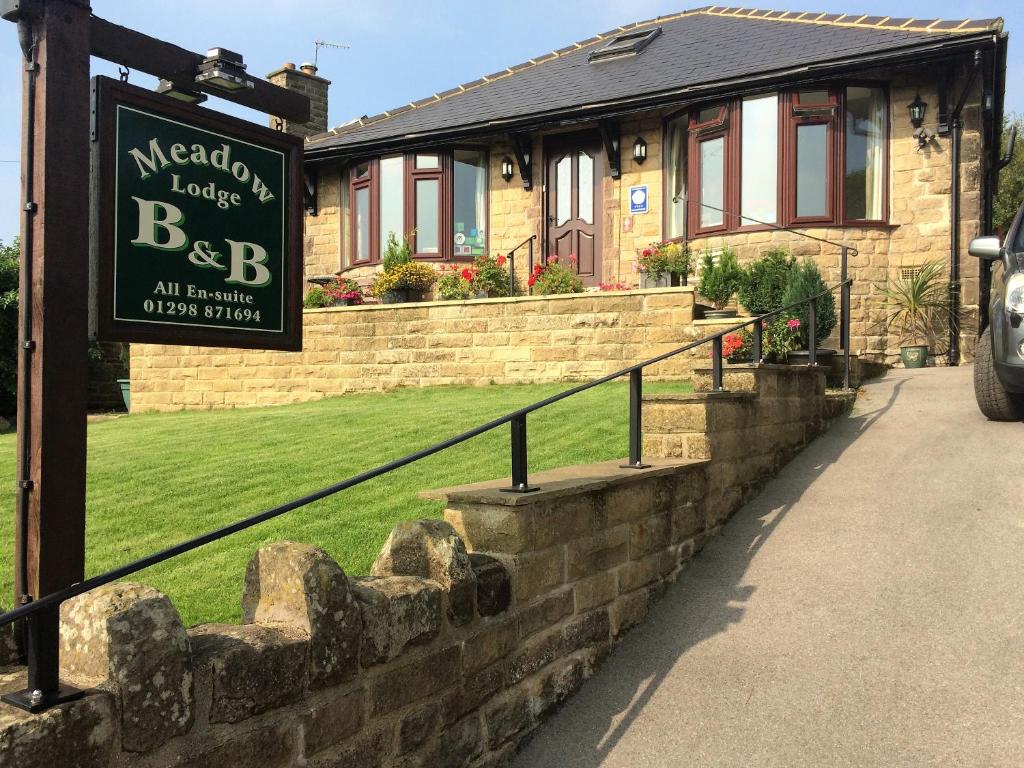 a sign in front of a brick house at Meadow Lodge in Tideswell