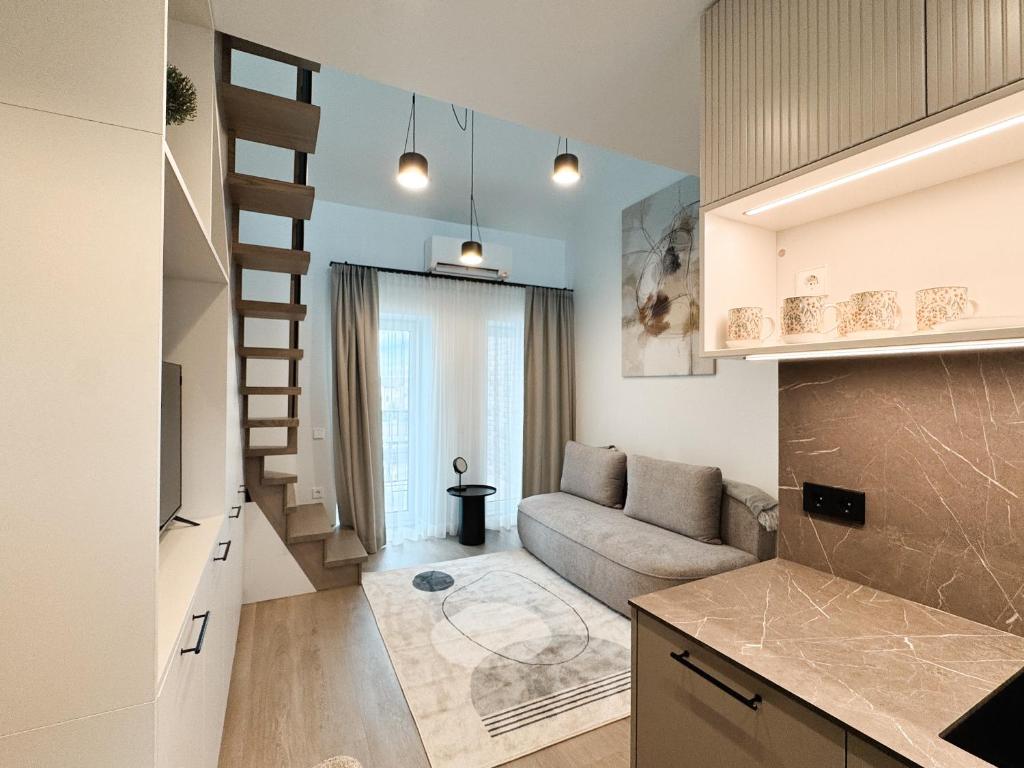 a kitchen and living room with a couch and a staircase at Jaukus loftas Šventoji in Šventoji