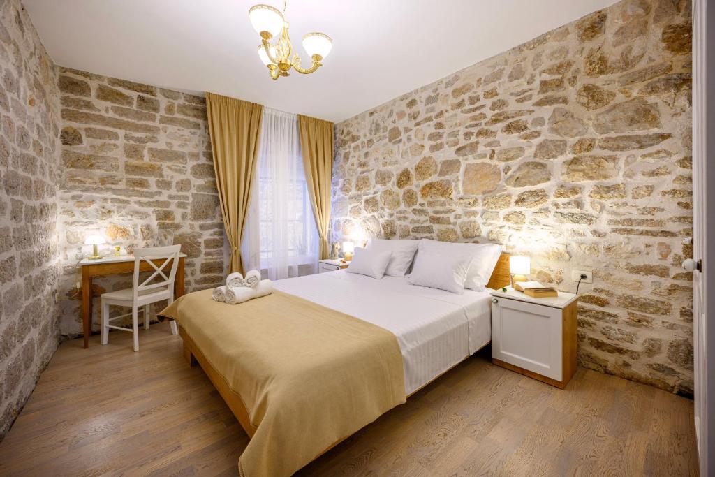 a bedroom with a bed and a stone wall at Apartments Festum in Šibenik