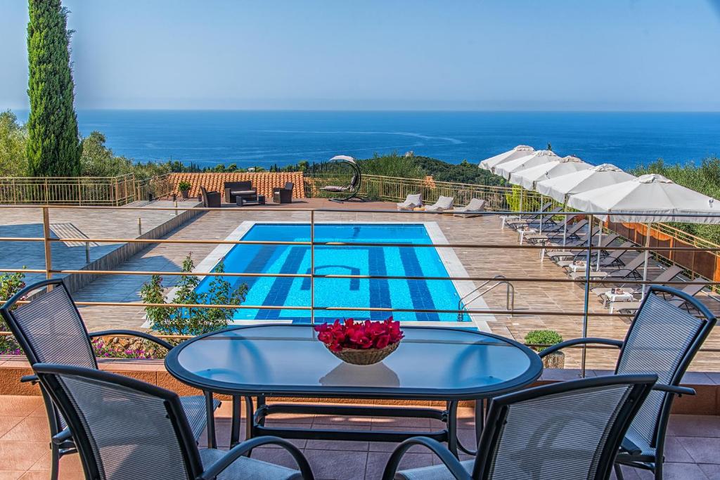 einen Tisch und Stühle auf einer Terrasse mit Pool in der Unterkunft Eltheo Villas in Agios Nikitas