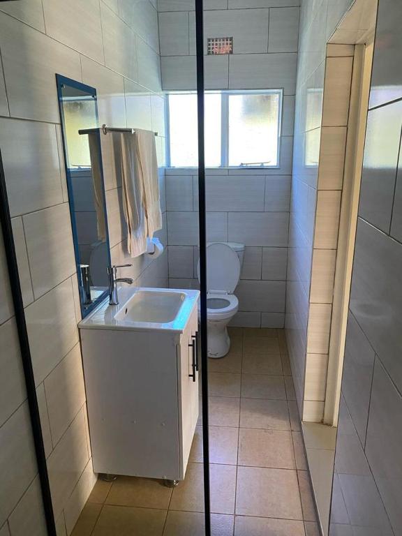 a white bathroom with a toilet and a sink at Wayekha Hotels in Kasungu