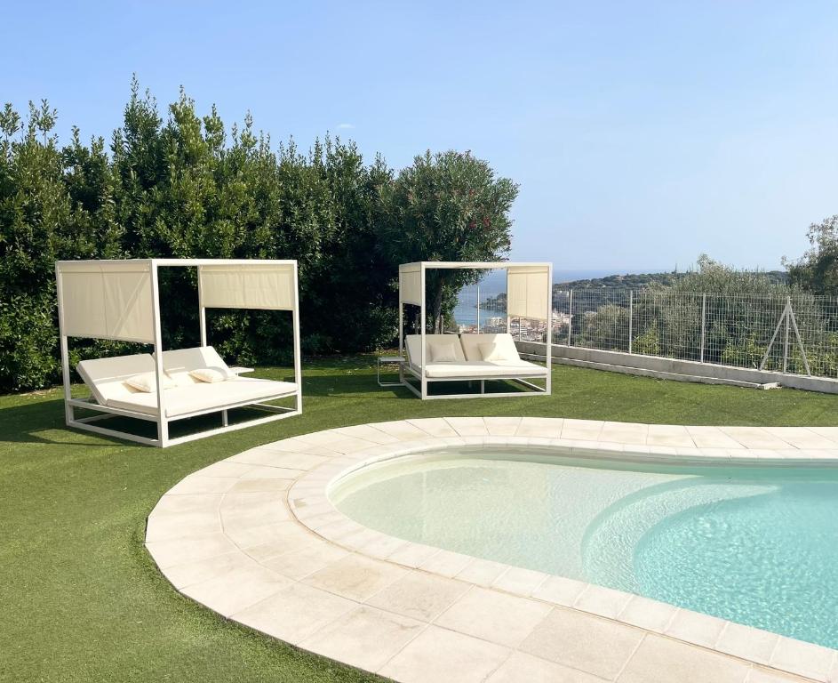 a swimming pool with two beds next to a swimming pool at Villa Le Clos des Lauriers in Roquebrune-Cap-Martin