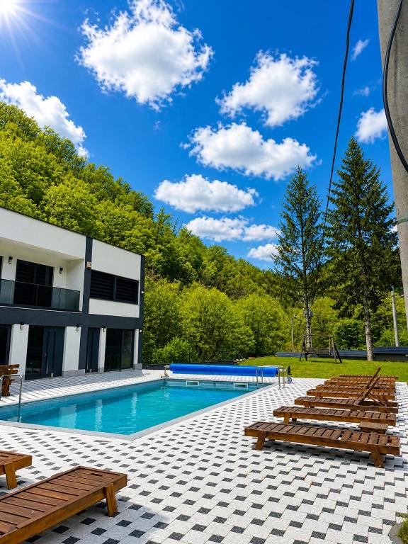 a swimming pool with wooden benches next to a building at Forest View Villa in Ilijaš