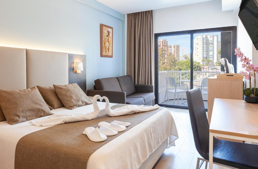 ein Hotelzimmer mit einem Bett, auf dem zwei Paar Sandalen lagen in der Unterkunft Hotel Golden in Benidorm