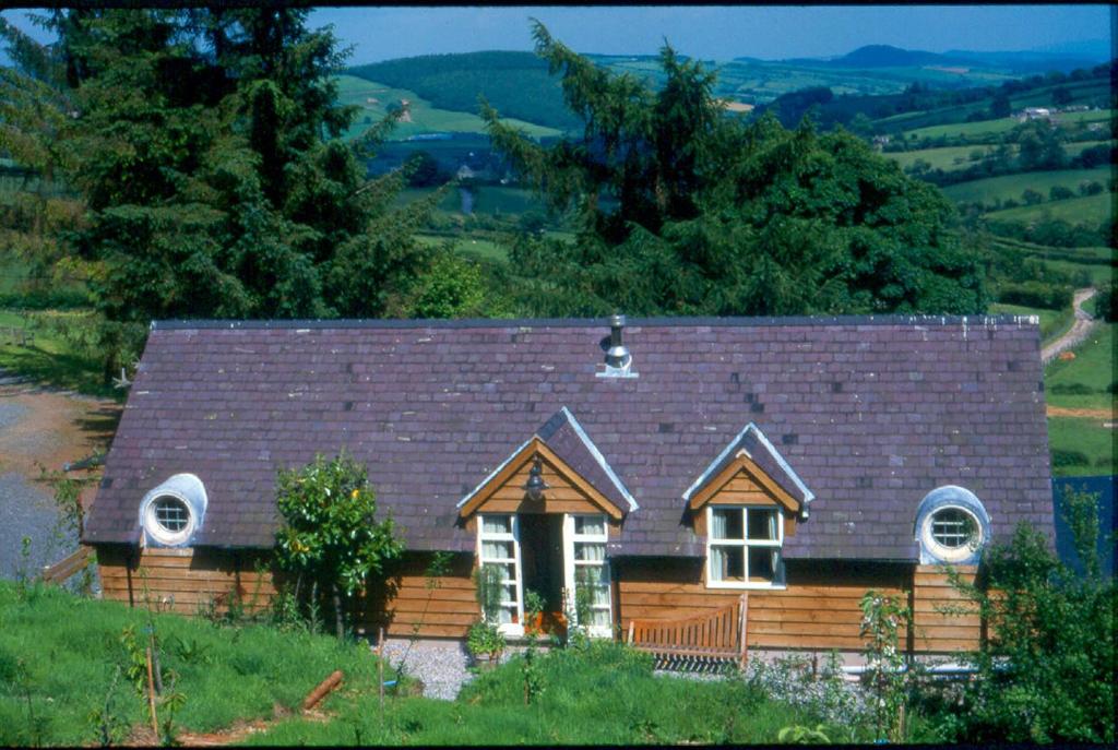 a wooden house with a brown roof on a hill at The Dick Turpin Cottage in Clun