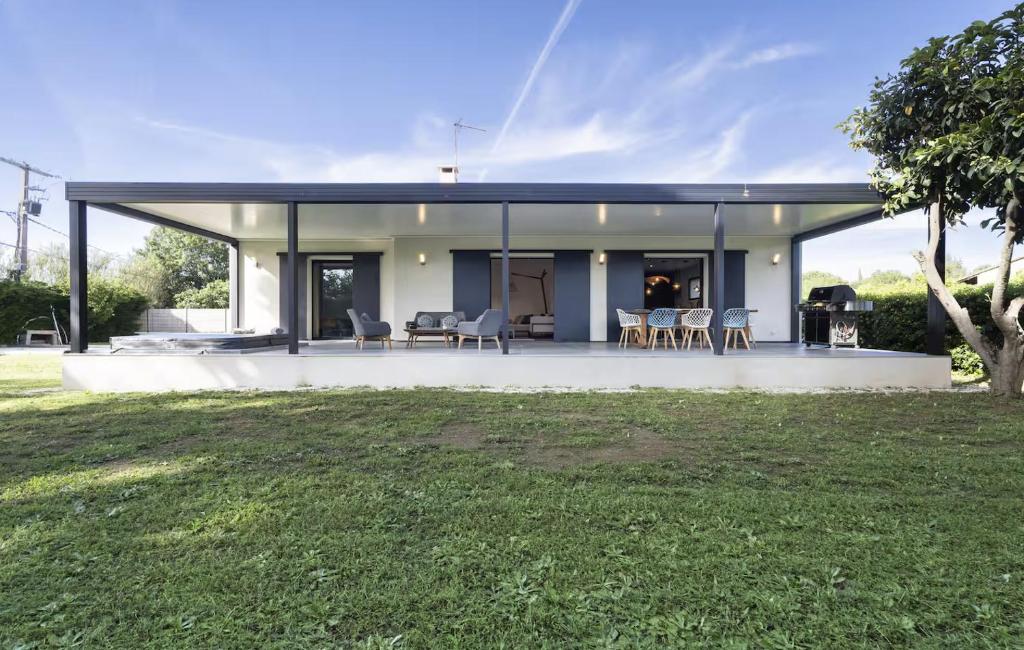a large white house with chairs and a yard at Villa bord de mer piscine, jacuzzi in Hyères