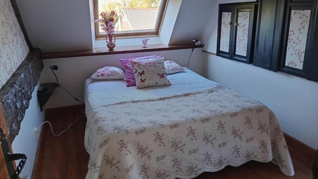 a small bedroom with a bed with pink pillows at Au cottage normand in Saint-James