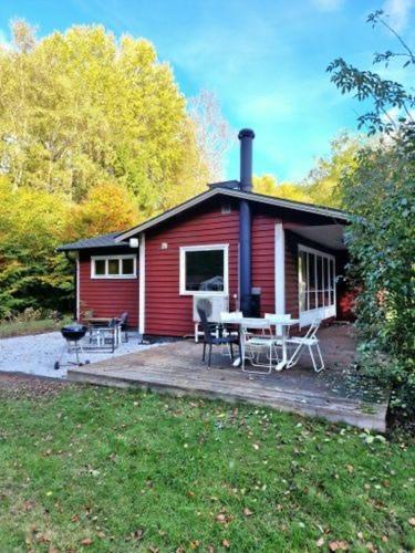 a red house with a picnic table and a grill at Skogsnära boende i Ludvigsborg in Ludvigsborg
