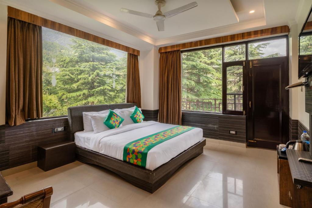 a bedroom with a bed and large windows at Treebo Holiday Hill in Dharmsāla
