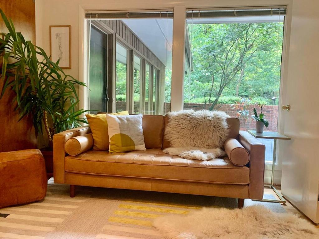 a couch in a living room with a large window at Mid-Century Gem Creekside King Beds Near UNC in Chapel Hill