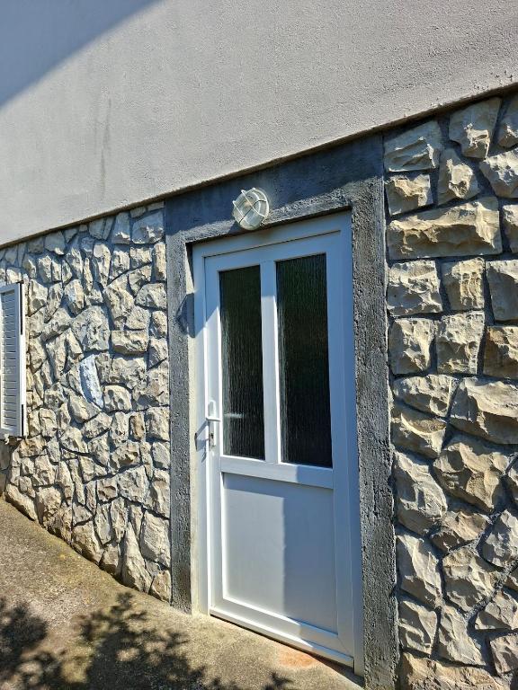 a stone building with a blue door and a stone wall at Rose Zaglav in Zaglav