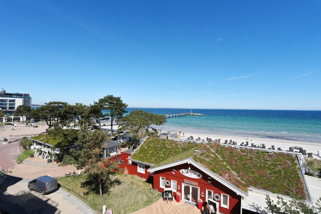 a red building with a grass roof on the beach at Residenz Ostseestrand Appartement 29 in Scharbeutz