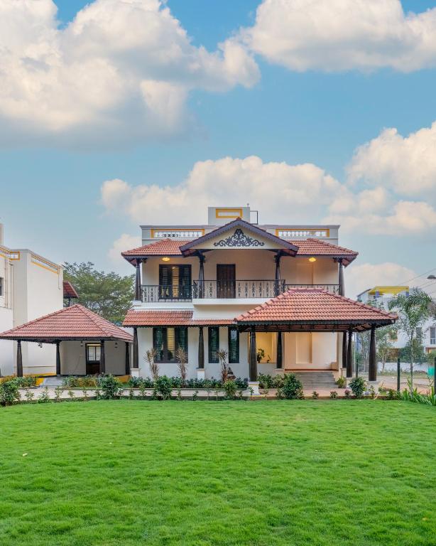 a large house with a green lawn in front of it at Nadhima Villas in Kumbakonam