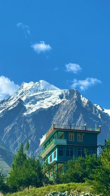 a building on a hill with a snow covered mountain at Kepal Inn Hotel and Restaurant in Holshāl