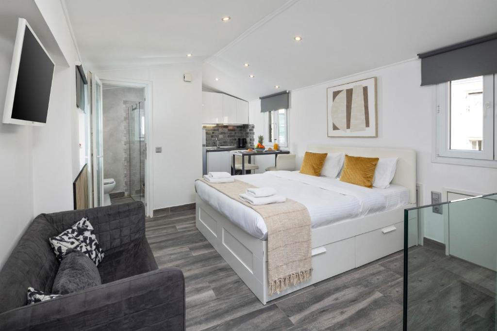 a white bedroom with a large bed and a couch at The Loft by Life Homes in Corfu