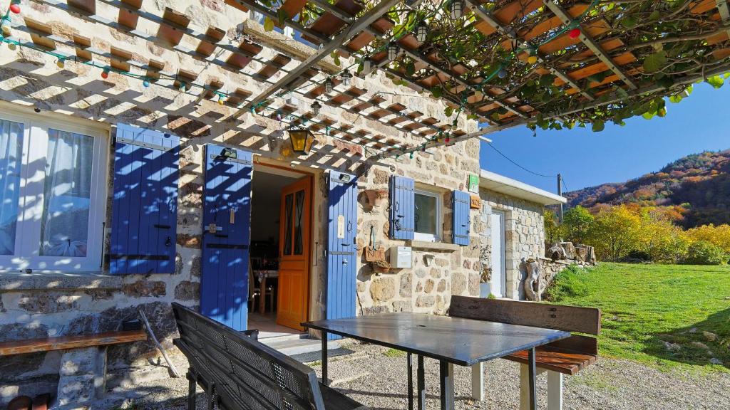 a table sitting outside of a house with a pergola at Gîte de NOE au Ray-pic in Péreyres