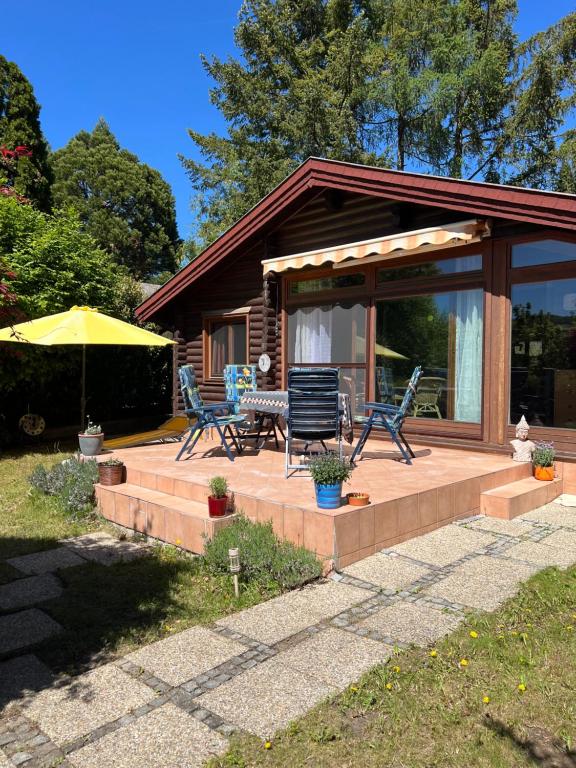 a house with a deck with chairs and an umbrella at See Paradies am Keltenberg in Wiesen