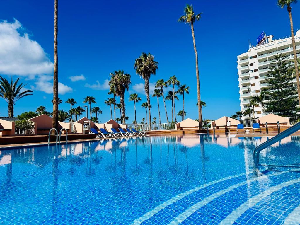 a large swimming pool with palm trees and a building at ACAPULCO AMAZING VIEWS. POOL. FREE WIFI in Playa Fañabe