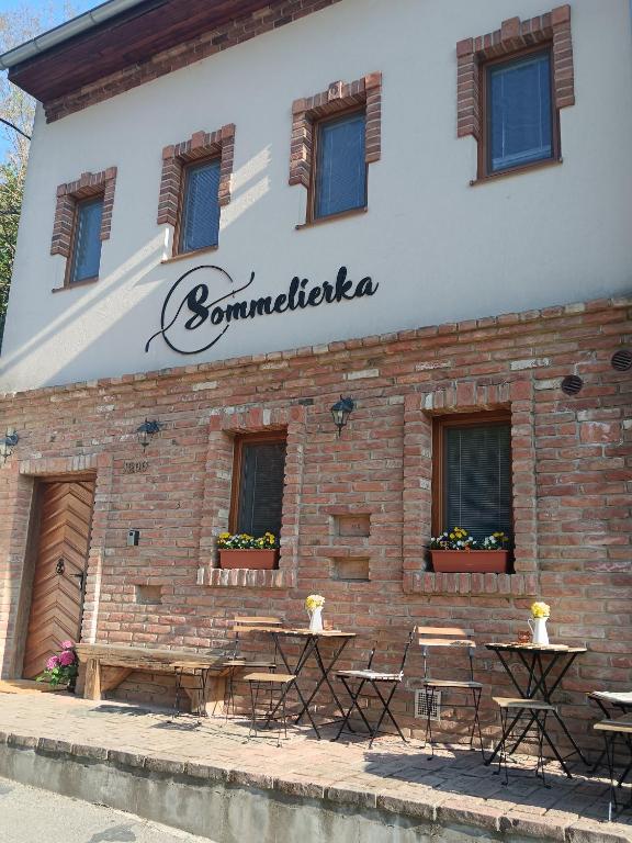 a brick building with tables and chairs in front of it at Sommeliérka - ubytování & vinný sklep in Valtice