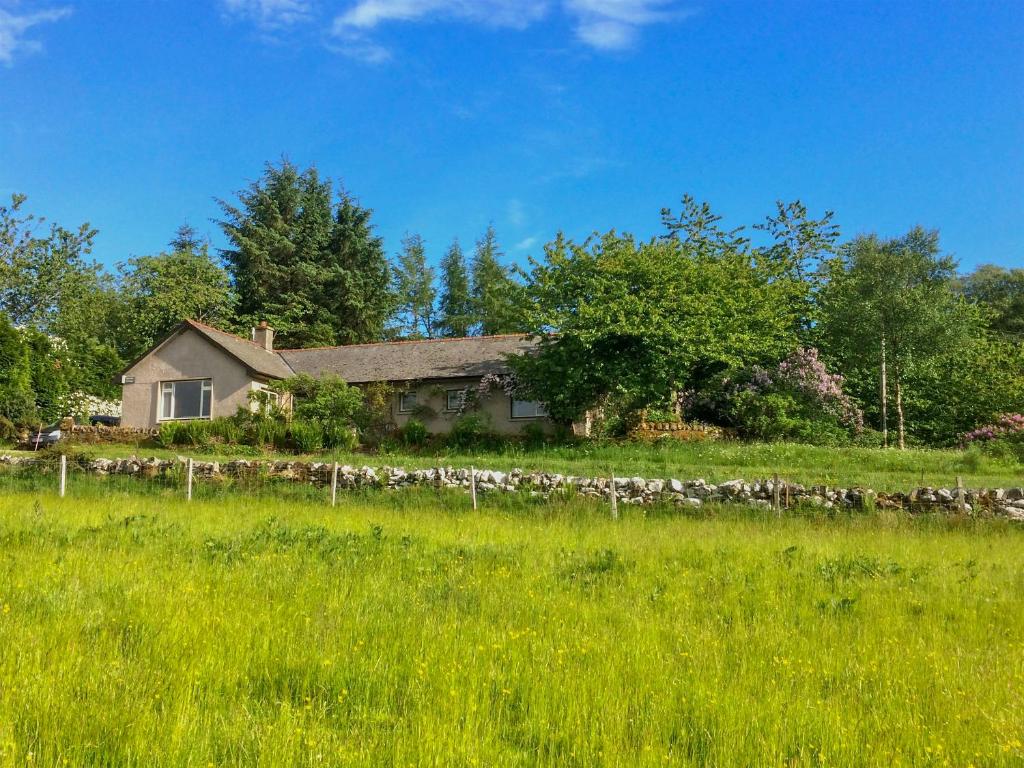 a house in a field with a stone fence at Garrique Cottage in Kippen