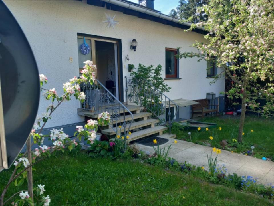 a white house with a porch with a staircase and flowers at Haus Bergrose in Busenborn